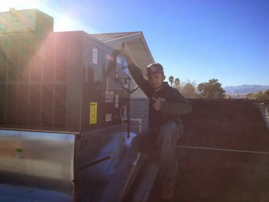 HVAC technician performing Air Duct Cleaning on a rooftop unit in Homewood